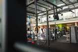 Moderner Fitnessbereich mit Functional-Training-Rack, Turnringen und Kraftgeräten in einer hellen, offenen Studioatmosphäre.