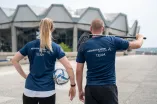 Mitsrbeiterin und Mitarbeiter des Hochschulsports mit Sportgeräten vor dem Audimax.