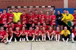 Die Handballherren und -damen der RUB stehen und sitzen in und um ein Handballtor zusammen mit ihren Trainern.