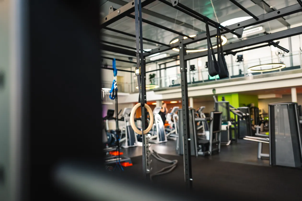 Moderner Fitnessbereich mit Functional-Training-Rack, Turnringen und Kraftgeräten in einer hellen, offenen Studioatmosphäre.