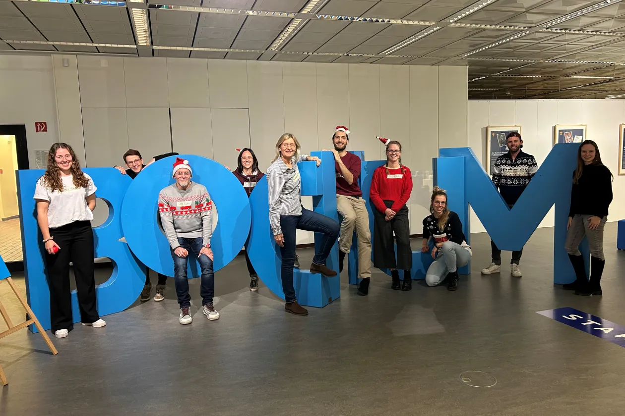 Ten people (the university sports team) are standing in oversized letters that spell out the word “Bochum.” 