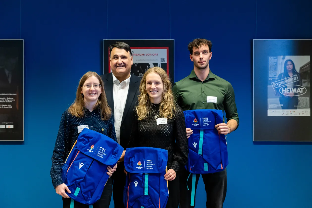 Carina Jadjewski, Laura Heinemann und Constantin Rutsch posieren für ein Gruppenbild der Obleute gemeinsam mit dem Rektor der RUB, Martin Paul, bei der Sportlerehrung 2025.