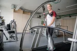 Die Spitzensportlerin Caroline Arft steht mit einem Kanupaddel auf einem Laufband.