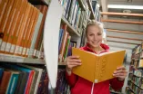 Die Spitzensportlerin im Rudern Michaela Staelberg steht in der Biblithek mit einem Buch in der Hand. Neben ihr steht ein Ruder.