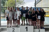 Die 6x50m Schmetterling Mixed Staffel steht zusammen auf dem Siegerpodest
