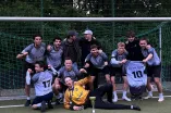 The Ruhrpott-PANNA team is celebrating wildly on the artificial turf field at Bochum University Sports after their victory in the final. Holding aloft the trophy, medals, and a jersey, the team proudly poses after a perfect season and winning the championship.