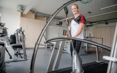 Die Spitzensportlerin Caroline Arft steht mit einem Kanupaddel auf einem Laufband.