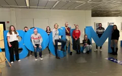 Ten people (the university sports team) are standing in oversized letters that spell out the word “Bochum.” 