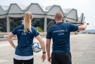 Mitsrbeiterin und Mitarbeiter des Hochschulsports mit Sportgeräten vor dem Audimax.