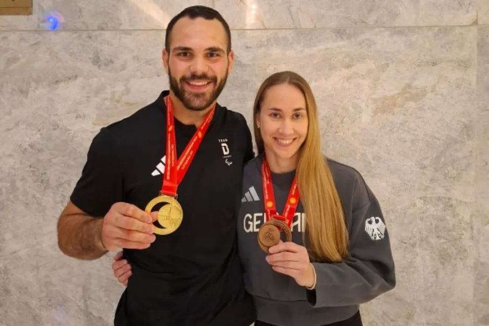 Isabell Thal with her teammate Lennart Sass. Both show their medals to the camera.