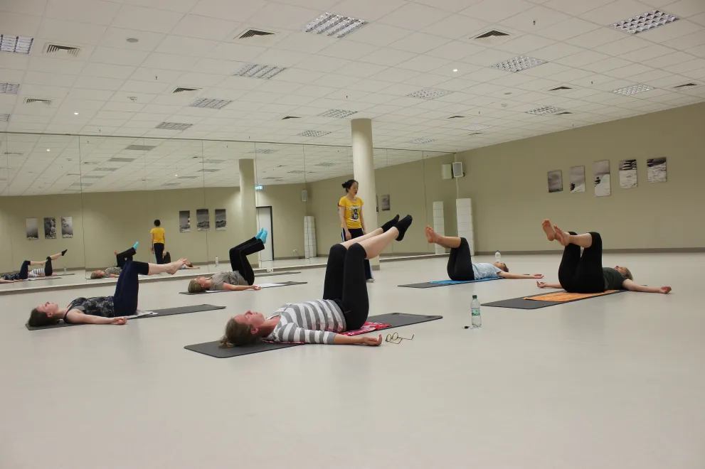Fünf Personen liegen auf dem Rücken und machen Kraftübungen mit ihrem Körper