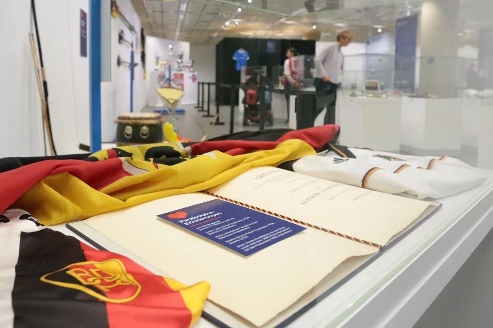 Ein Tisch auf dem eine Deutschlandfahne und weitere Gegenstände mit Sportbezug liegen.